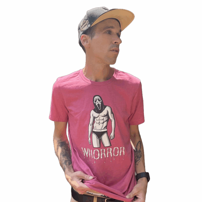 A man stands outdoors wearing a tan cap and a pink Whorror t-shirt with an illustrated male figure in underwear and a scream mask.