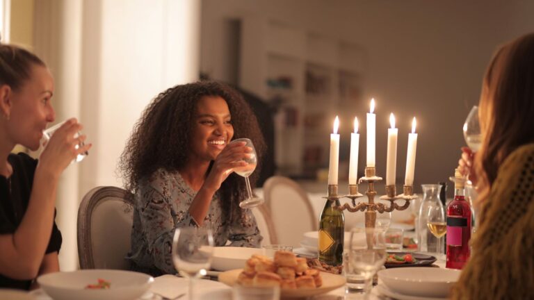 Friends gathered around a candlelit dinner table sharing a meal