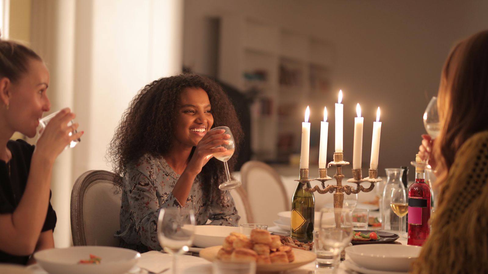Friends gathered around a candlelit dinner table sharing a meal
