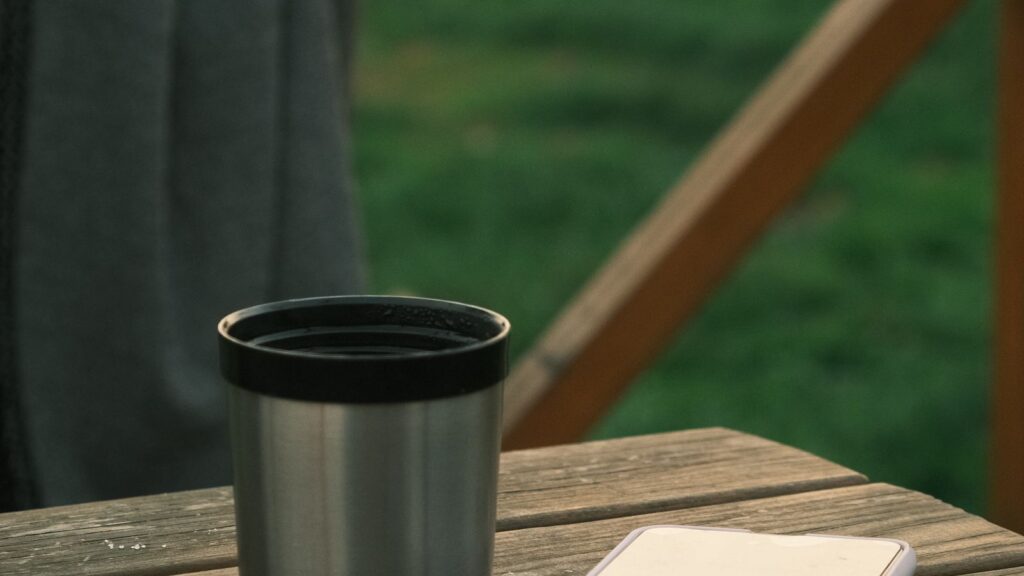 A smartphone resting on a table beside a coffee cup in soft light