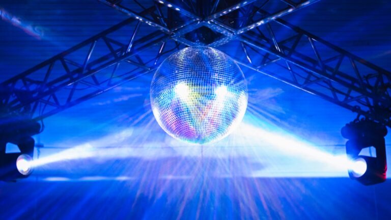 A disco ball casting colorful light across a lively party room