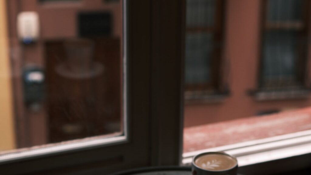Two coffee cups on a table by a window in calm, conversational light